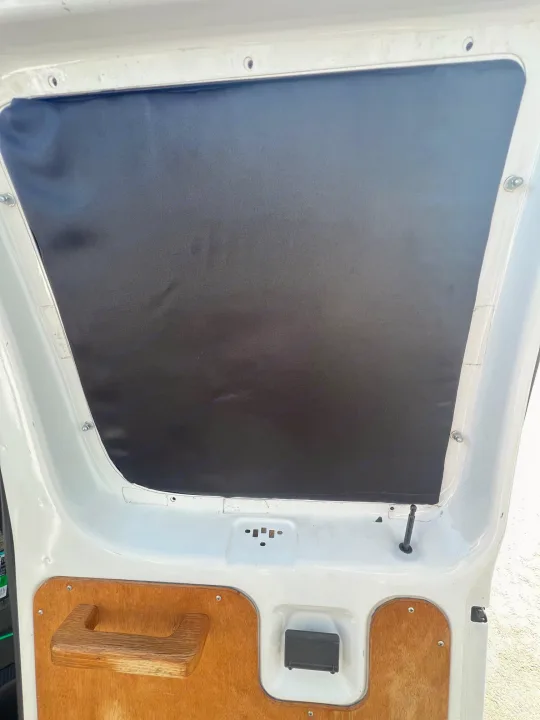Inside an RV rental van door, featuring a black privacy cover, custom wooden handle, and wood paneling.. Ford Econolline 250s 2006