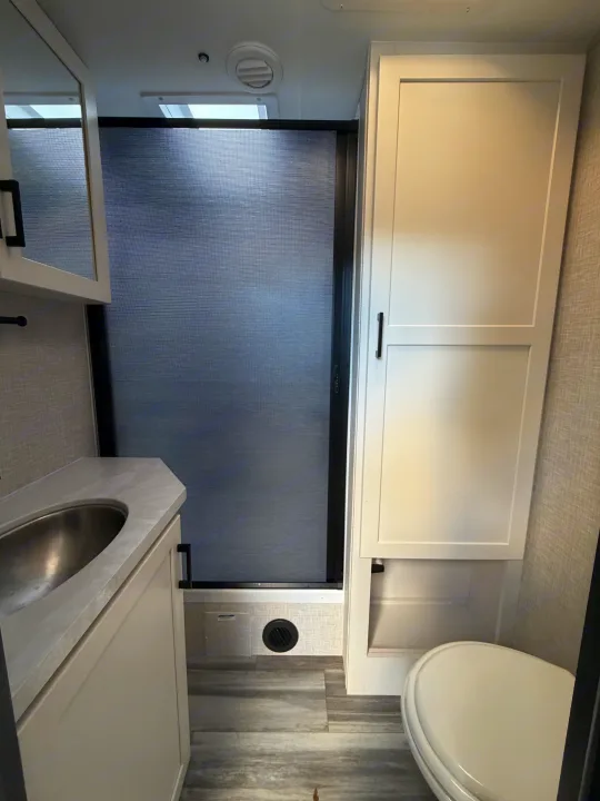Modern RV rental bathroom: a compact space featuring a sink, retractable shower, and toilet for your travel convenience.. Jayco Eagle HT 2025