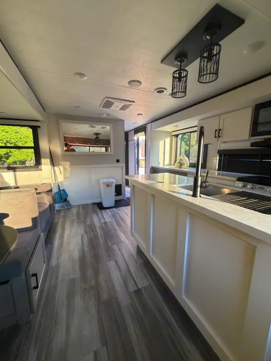 Inside this modern rv rental, find a bright kitchen with island, living area, sleek fixtures, and wood-look flooring.. Jayco Eagle HT 2025
