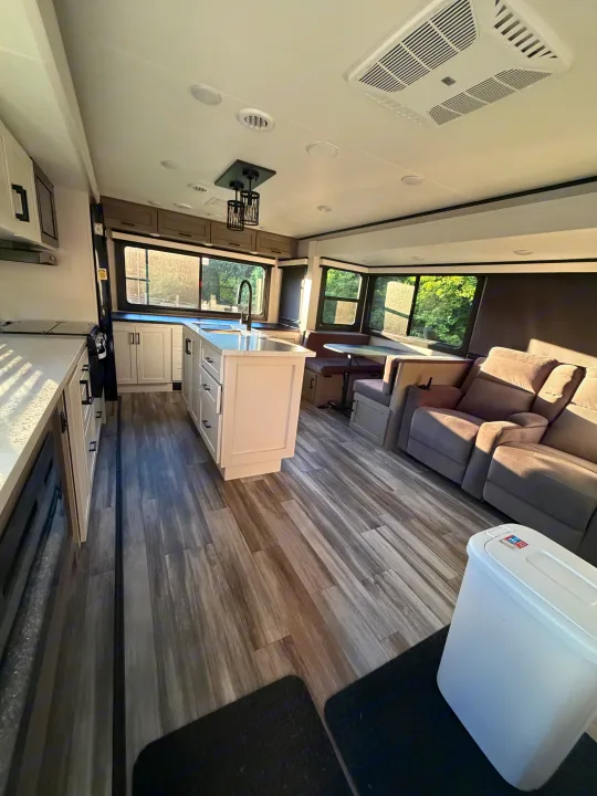 Spacious, sunlit RV rental interior with a modern kitchen island, dining booth, and comfortable living area.. Jayco Eagle HT 2025