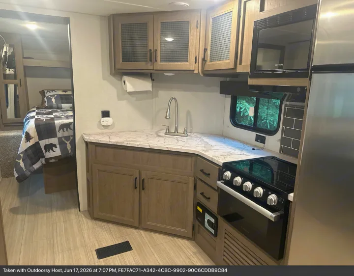This RV rental showcases a well-equipped kitchen with a sink, stove, & microwave, and a cozy bedroom with bunk beds & themed bedding.. Keystone RV Hideout Luxury 2021