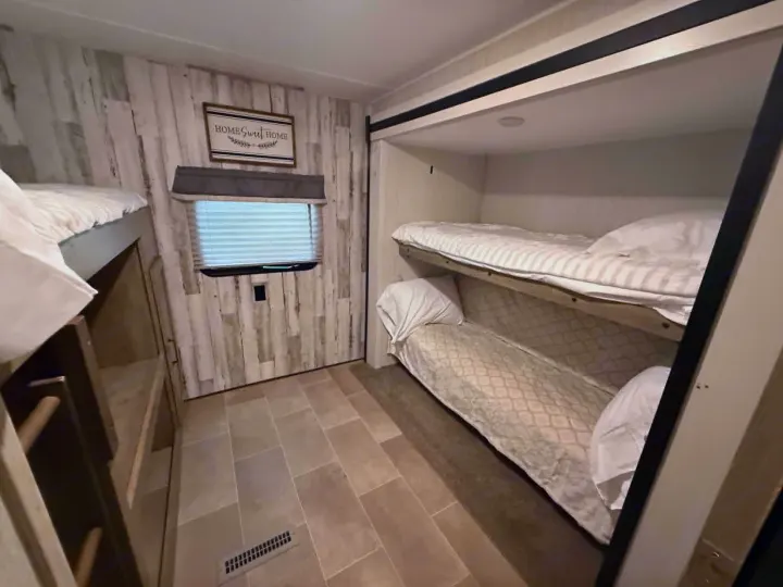 Charming RV rental bunk room with stacked beds, rustic walls, and a window, offering ample sleeping for guests.. Forest River Palomino Puma XLE Lite 2021