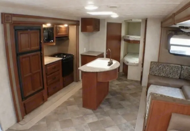 Spacious rv rental interior with a full kitchen including an island sink, bunk beds, and a comfortable dinette.. Palomino Puma 2015