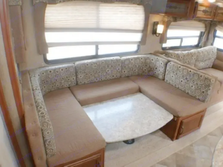 Cozy U-shaped dinette with patterned cushions, a table, and windows, perfect for your next RV rental adventure.. Palomino Puma 2015