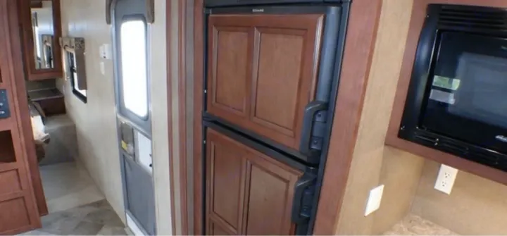 RV rental interior: Kitchen with a wood-paneled fridge, microwave, and a visible entry door. Great for your next adventure.. Palomino Puma 2015