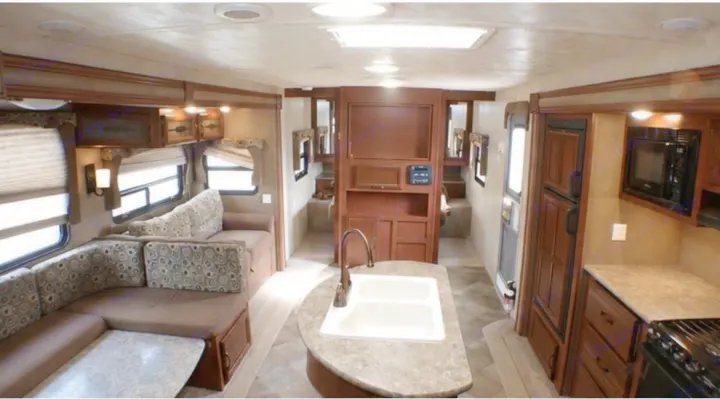 Spacious RV rental interior: U-shaped dinette, kitchen island with sink, fridge, microwave, and rear bunk beds.. Palomino Puma 2015