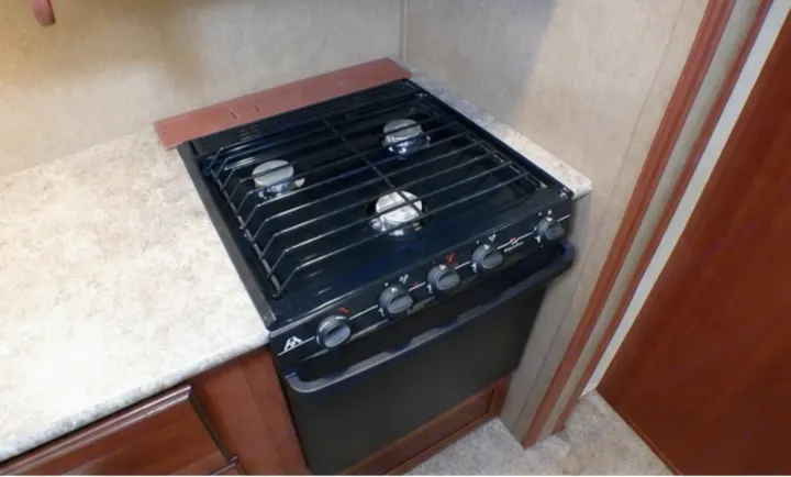 Compact gas stove and oven in an RV rental kitchen, ideal for cooking on the go. Features three burners and control knobs.. Palomino Puma 2015