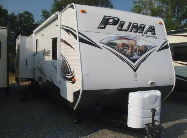 White Puma travel trailer RV rental, featuring a front graphic of a puma & cubs, with an extended slide-out for space.. Palomino Puma 2015