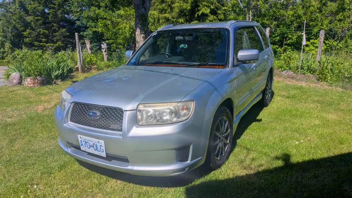 A silver Subaru Forester SUV parked on green grass. Ideal for local adventures, or try an RV rental for extended journeys.. Subaru Forester 2009