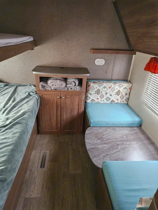RV rental interior: bunk bed, storage cabinet, blue dinette seating with patterned pillow & table.. Heartland RVs Prowler 2018