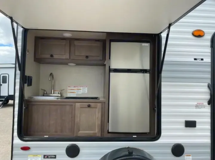 This RV rental features a well-equipped outdoor kitchen: sink, cabinets, and a spacious double-door refrigerator for your adventures.. Sunset Park RV SunRay 2022