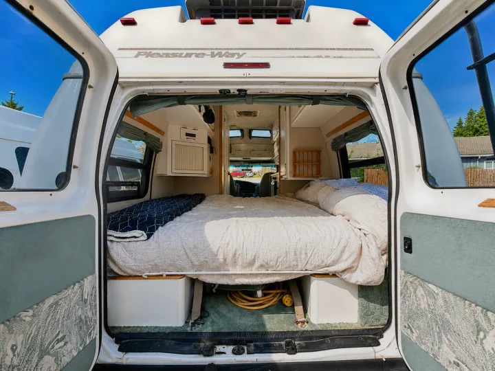 Explore this Pleasure-Way RV rental's cozy interior, featuring a comfortable bed for your next camper van adventure.. Pleasure-Way Pleasure-Way Class B 2002