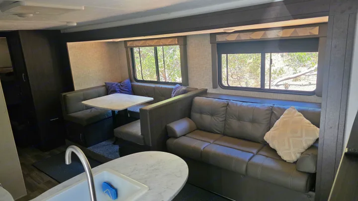 Spacious RV rental interior featuring a cozy dinette, comfortable sofa, and modern kitchen sink area.. Forest River Wildwood X-Lite 2019