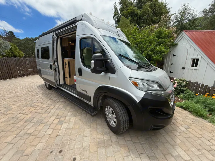 Silver Pixel RV rental camper van parked on a paved driveway, its side door open to reveal the interior.. Coachmen Pixel 2025
