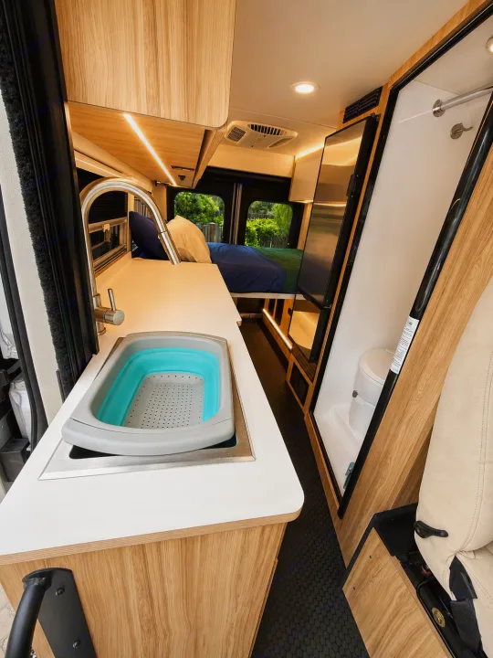 Inside this RV rental: a modern kitchen with a foldable sink, comfortable bed, and compact bathroom setup.. Coachmen Pixel 2025