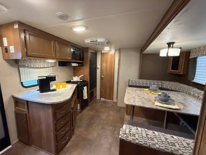 Bright RV rental interior features a compact kitchen with coffee maker & stove, plus a comfy dinette for meals.. Coachmen Apex Ultra Lite 2016