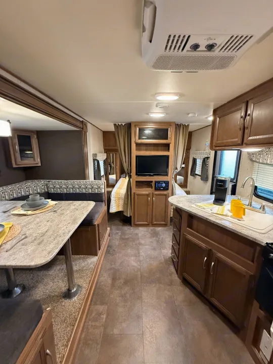Inside this cozy RV rental: a well-appointed dinette, kitchen with Keurig, TV entertainment, and curtained sleeping area.. Coachmen Apex Ultra Lite 2016