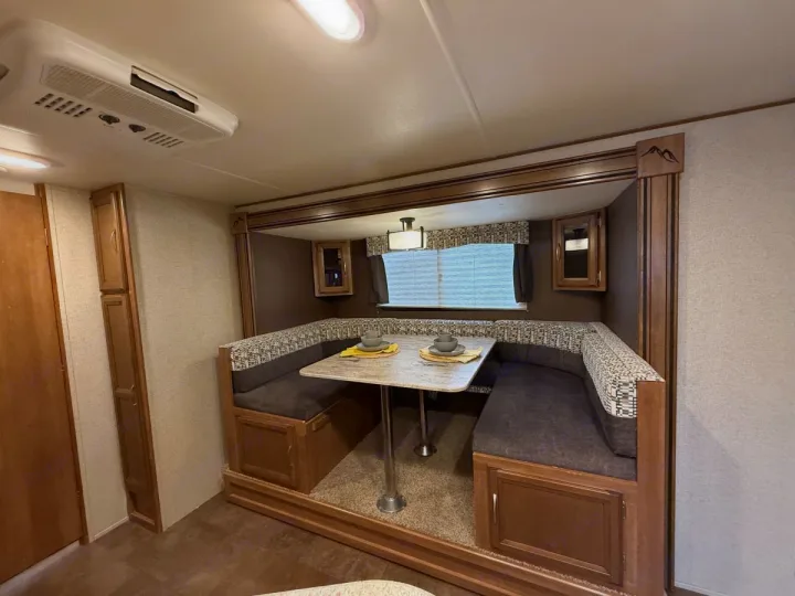 This RV rental features a comfortable dinette with booth seating, a table set for two, and overhead cabinets for storage.. Coachmen Apex Ultra Lite 2016