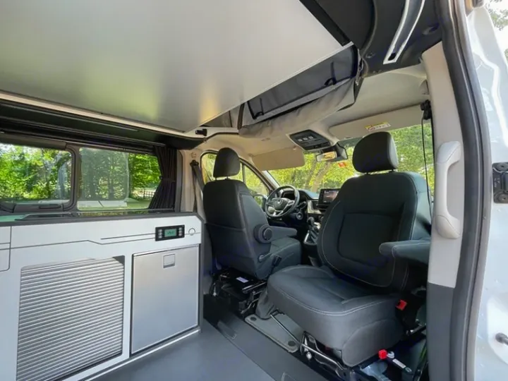 Interior of an rv rental campervan: features front cabin, raised pop-top roof, and a sleek kitchenette with fridge.. HANROAD TREK 5 2026