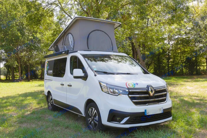 A modern white camper van with a raised pop-top roof, available for rv rental, sits on green grass under trees on a sunny day.. HANROAD TREK 5 2026