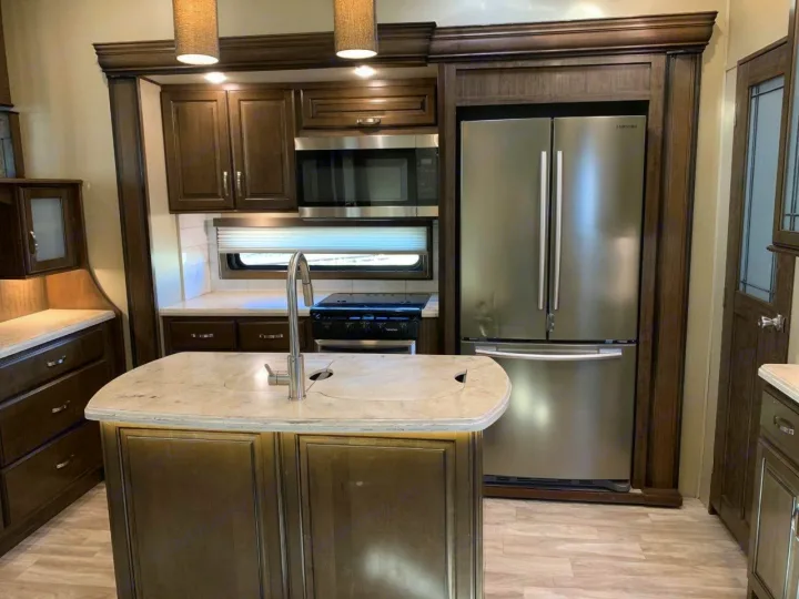 Fully equipped rv rental kitchen, featuring a Samsung fridge, microwave, stovetop, and island with sink.. Grand Design Solitude 2018