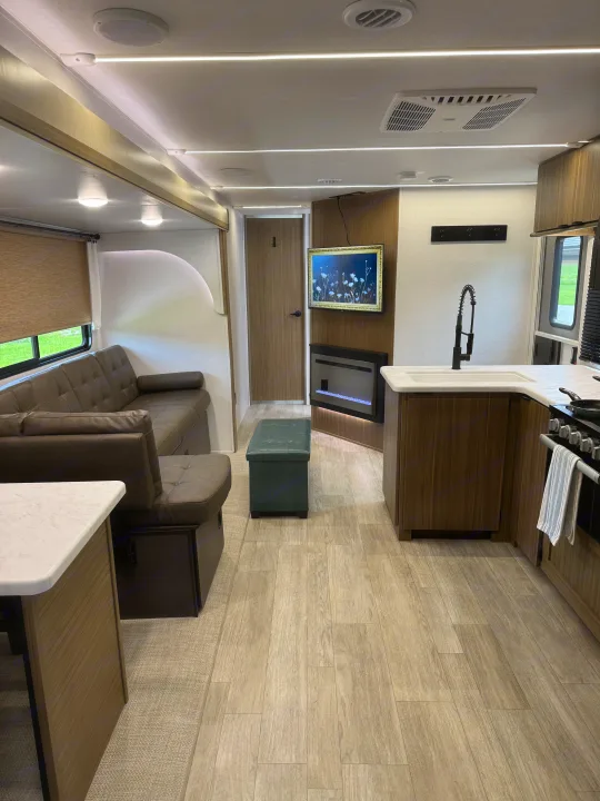 Modern RV rental interior with a living room sofa, kitchen area, fireplace, TV, and stylish lighting.. Forest River Wildwood FSX Platinum 2026