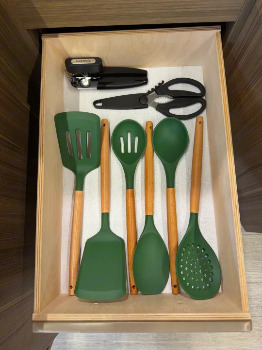 Organized kitchen drawer in an RV rental with Farberware can opener, shears, & green silicone cooking utensils.. Forest River Wildwood FSX Platinum 2026