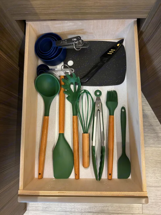 Well-organized kitchen drawer in this RV rental, featuring green & blue utensils for compact living.. Forest River Wildwood FSX Platinum 2026