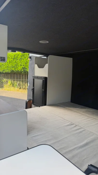 Cozy RV rental interior: featuring a compact bed, integrated fridge, and smart storage in a modern campervan design.. Renault TRAFIC 2020