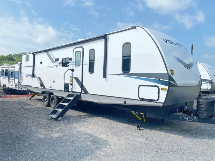 This modern white Volante travel trailer, perfect for an rv rental, is parked on gravel under a blue sky, ready for your next adventure.. Crossroads RV Volante 2023