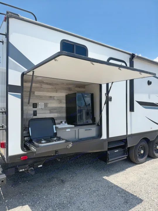 This RV rental offers an outdoor kitchen with a slide-out stove, sink, and mini-fridge for convenient al fresco dining.. Crossroads RV Volante 2023
