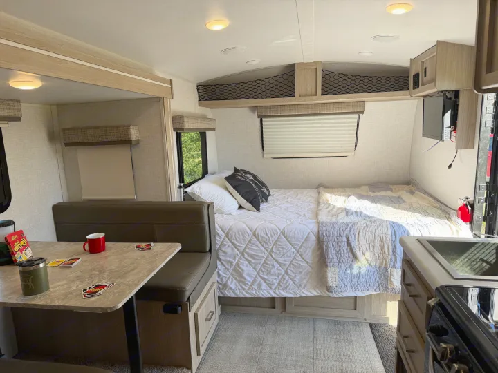 Cozy rv rental interior featuring a comfortable bed, dinette with games, and a compact kitchenette.. Forest River Flagstaff E-Pro 2022