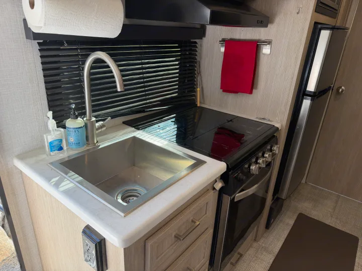 Clean and functional RV rental kitchenette, featuring a sink, stove/oven, compact refrigerator, and handy paper towels.. Forest River Flagstaff E-Pro 2022