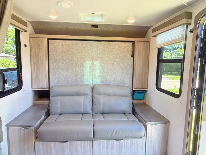 Inside this RV rental: a versatile sofa that converts to a bed, surrounded by practical storage and bright windows.. Minnie Micro Minnie 2021