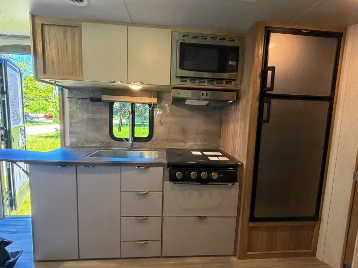Well-equipped RV rental kitchen: sink, stove, microwave, Dometic fridge, and light cabinets. Ready for your adventure.. Minnie Micro Minnie 2021