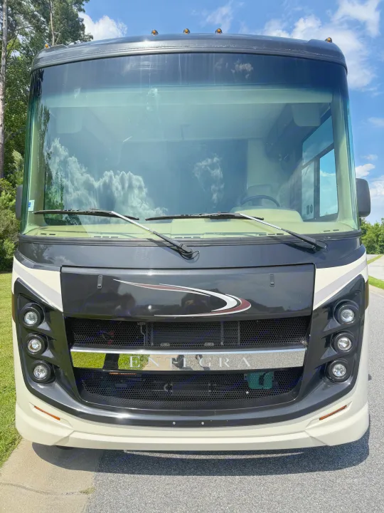Front view of a black and cream Entegra motorhome, showcasing its grille, stacked headlights, and large windshield. A premium rv rental option.. Entegra Coach Vision 2020