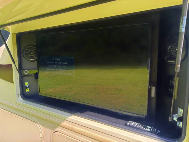 An RV rental's exterior entertainment system features a TV displaying "No Signal," alongside Furrion speakers and a stereo.. Entegra Coach Vision 2020