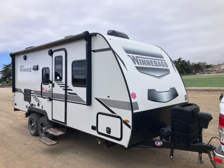 White Winnebago Micro Minnie travel trailer RV rental, parked on dirt. Great for camping adventures & road trips!. Winnebago Micro Winnie 2021