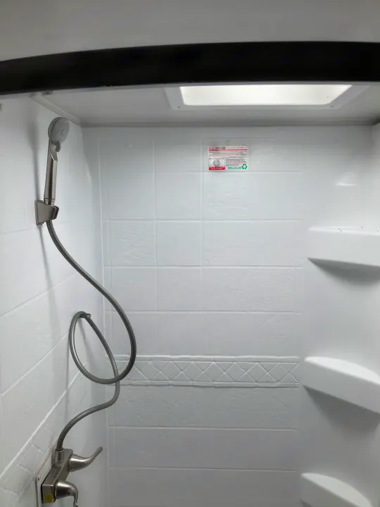 Inside an rv rental: a compact white shower stall with a handheld shower, dual-handle faucet, built-in shelves, and a skylight.. Winnebago Micro Winnie 2021