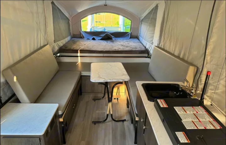 Inside this cozy pop-up RV rental: a comfortable bed, dinette with table, and a compact kitchen with sink and stove.. Forest River Viking LS 2022