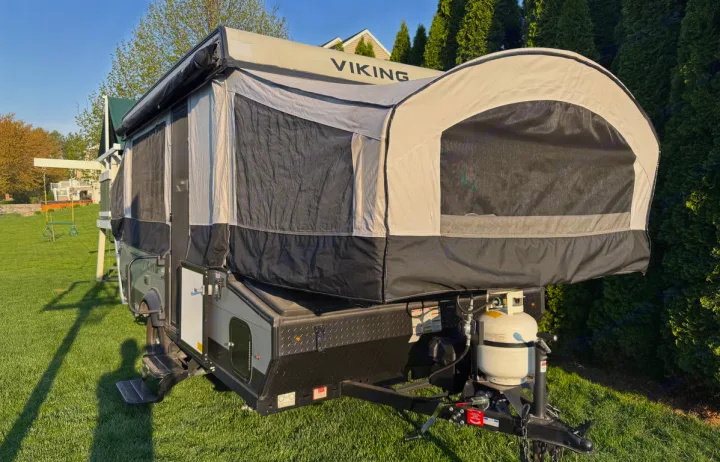 This fully extended, white and black pop-up RV rental is pictured on a sunny lawn, ideal for your next outdoor camping trip.. Forest River Viking LS 2022