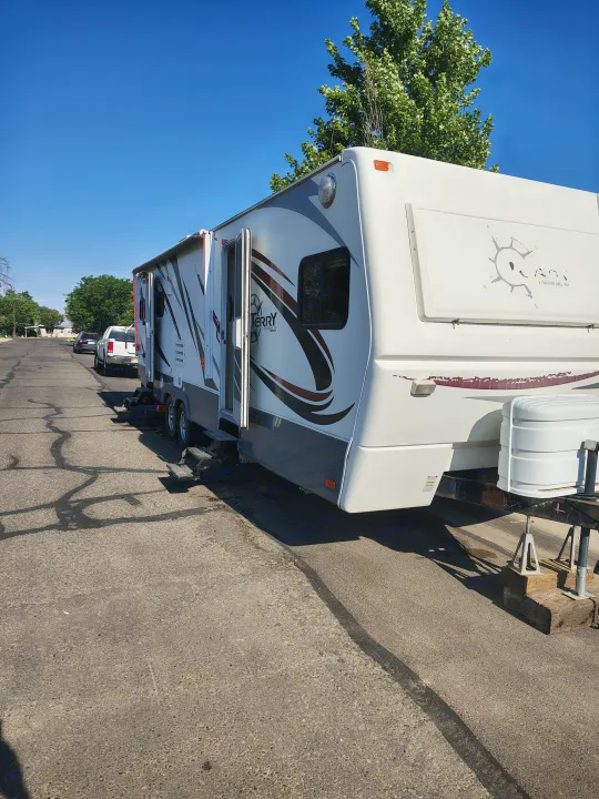 A white travel trailer RV with an open door and "TERRY" branding is parked on a sunny street. Ideal for your next RV rental getaway.. Fleetwood Terry 2007