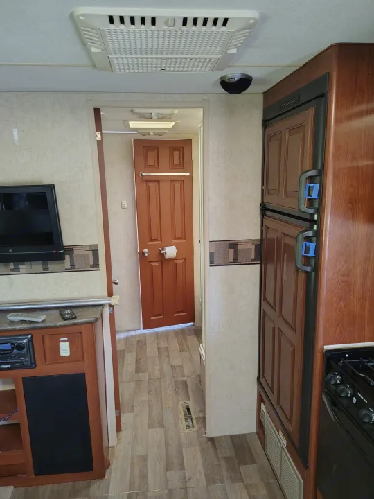 RV rental interior: fridge, entertainment center, partially open door, and overhead AC unit.. Fleetwood Terry 2007