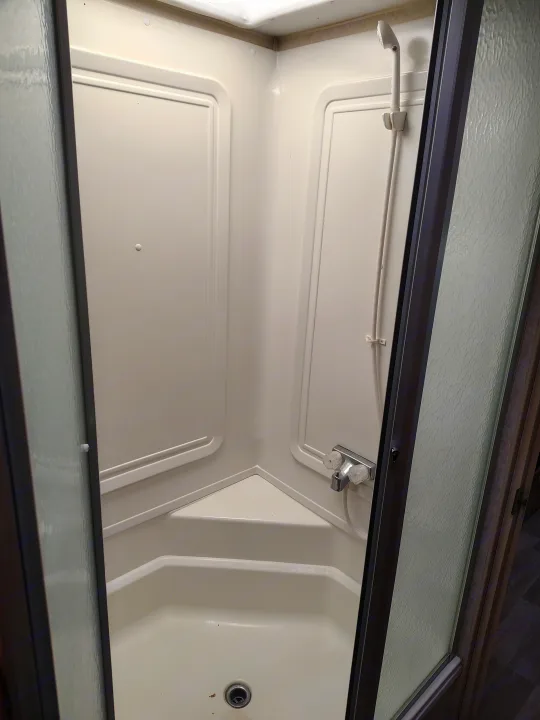 A clean, compact corner shower inside an rv rental, featuring a handheld showerhead and sliding glass doors.. Fleetwood Terry 2007