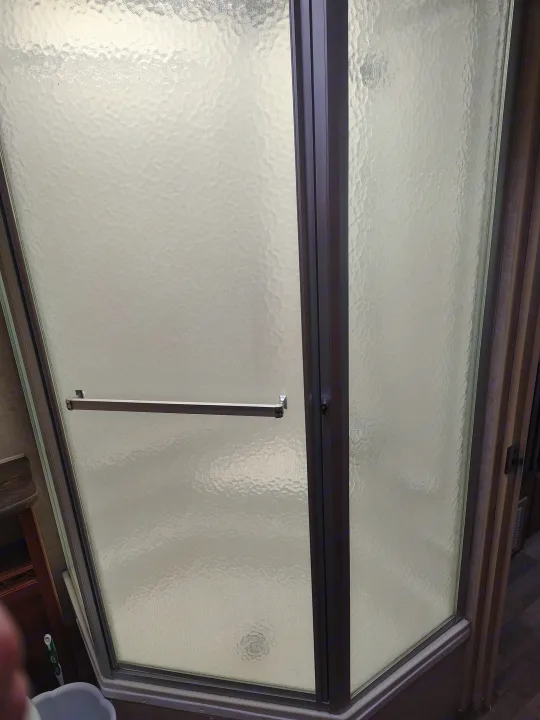 Frosted glass shower enclosure with dark frame and exterior towel bar in this RV rental. Perfect for your travels.. Fleetwood Terry 2007