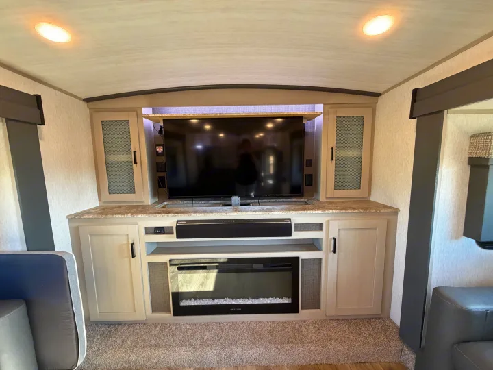 Cozy RV rental entertainment center featuring a TV, soundbar, and electric fireplace within a modern living area.. Forest River Salem Hemisphere 2023