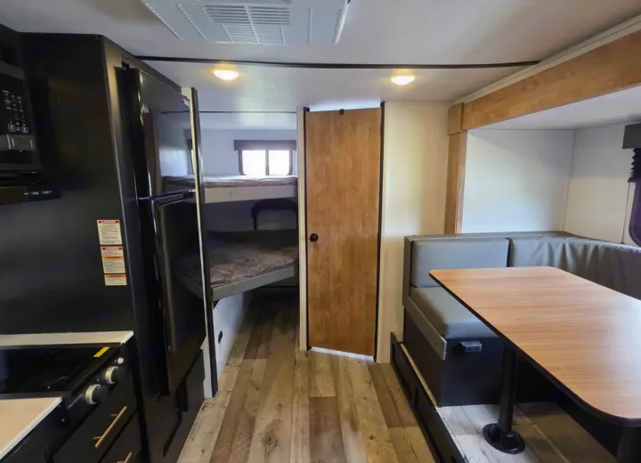 Inside this RV rental: a compact kitchen, bunk beds with windows, and a comfortable dinette. Ideal for travel and camping.. Keystone RV Springdale 2023