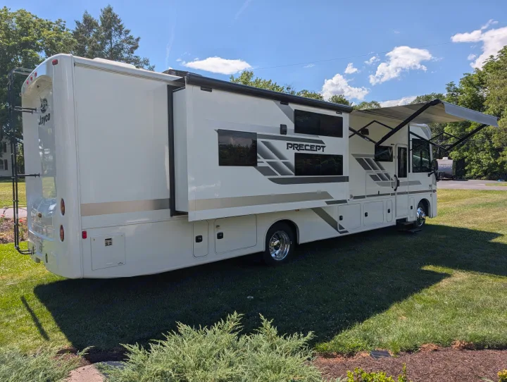 This Jayco Precept RV rental, with its slide-out and awning extended, sits on green grass under a blue sky, ready for adventure.. Jayco Precept 2025