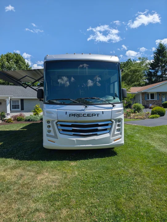 Front view of a white Precept Class A motorhome RV rental parked on a green lawn in a residential area under a blue sky.. Jayco Precept 2025