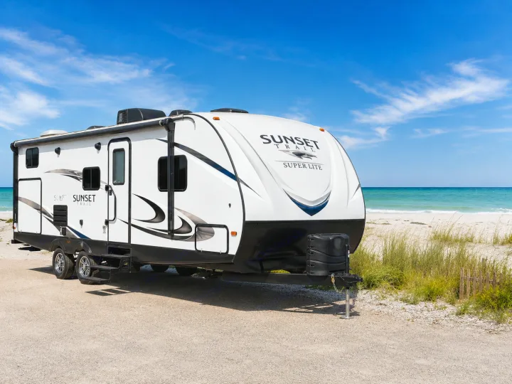 Experience coastal freedom with this Sunset Trail RV rental parked on a sunny sandy beach next to turquoise waters.. CrossRoads RV Sunset Trail Super Lite 2016